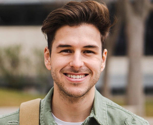 Smiling man in green shirt outdoors at Canton Healthy Smiles dental practice.