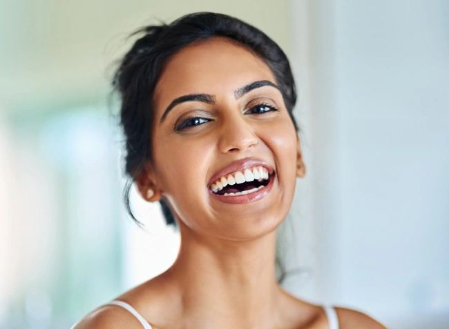 Woman smiling brightly at camera in clean, modern dental office setting.
