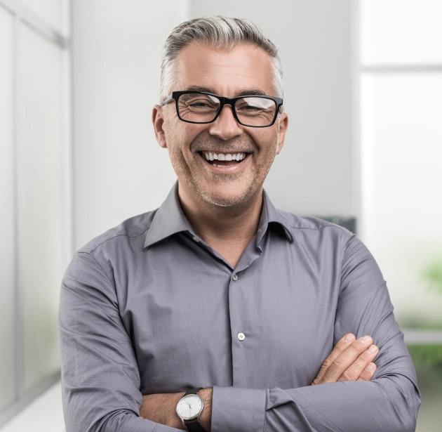 Professional man with glasses smiling, arms crossed, in bright office setting at Canton Healthy Smiles.