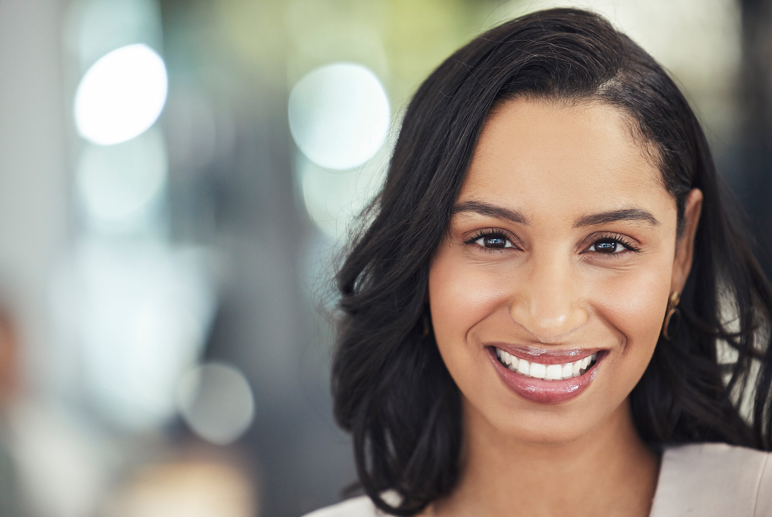 Woman smiling at camera in professional dental office setting with blurred background