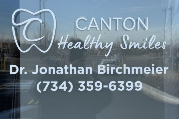 Canton Healthy Smiles dental office window signage displaying Dr. Jonathan Birchmeier's name and contact number.